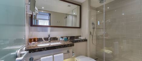 A modern bathroom with a glass-enclosed shower, a marble countertop, and a large mirror.