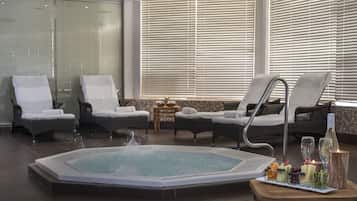 Un área de spa con un jacuzzi, sillones de descanso y una mesa con frutas y velas.