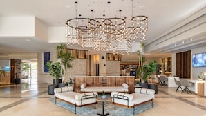 En moderne lobby med en hjørnesofa, et rundt sofabord og en stor lysekrone.