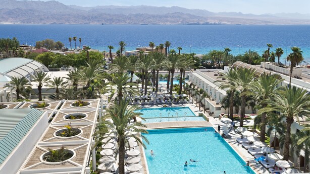 A resort with a large pool, palm trees, and a view of the sea. - Yam Suf by Isrotel Collection (Eilat)
