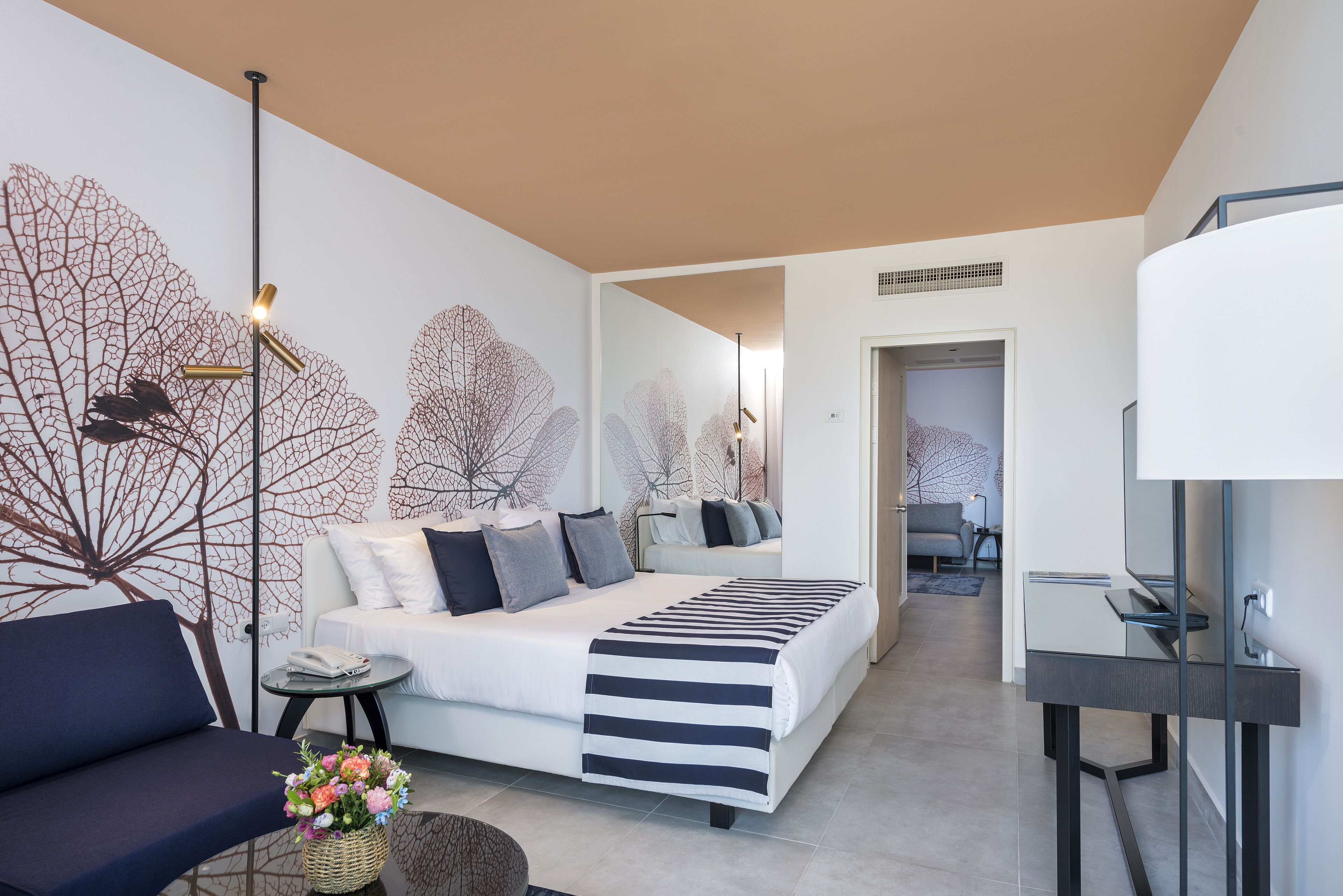 Un dormitorio moderno con cama, sofá, mesita de noche y lámpara.