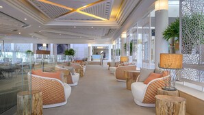 A modern lobby with sofas and tables, a reception desk, and decorative plants. - Yam Suf by Isrotel Collection (Eilat)