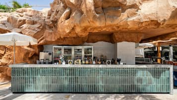 Un espace bar avec un mur en pierre, un comptoir carrelé et une variété de bouteilles et de verres.