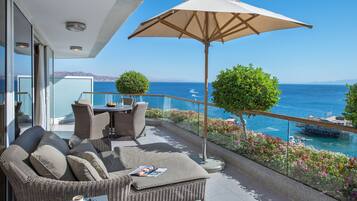 A balcony with wicker furniture, a table with a magazine, and a large umbrella.