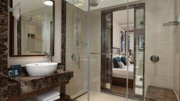 A modern bathroom with a glass-enclosed shower, a large mirror, and a marble countertop.