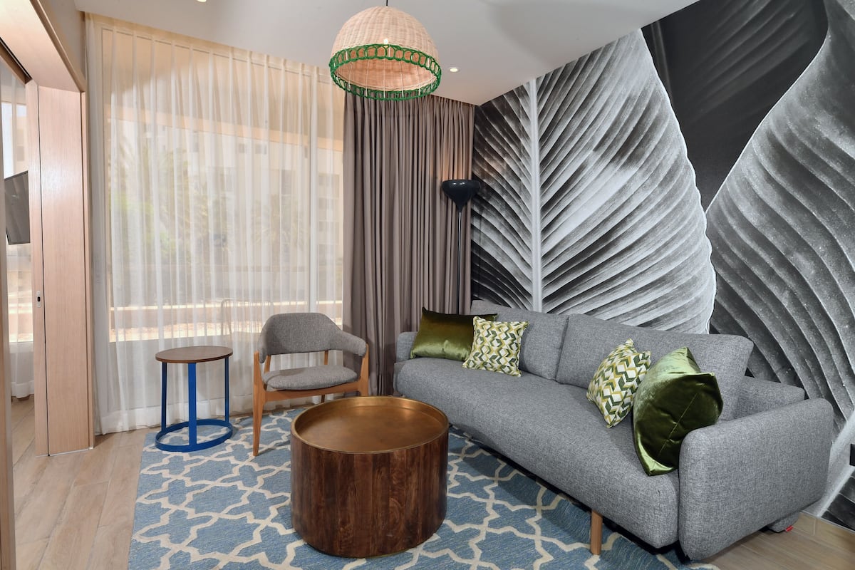 A modern living room with a grey sofa, patterned rug, and a round wooden coffee table.