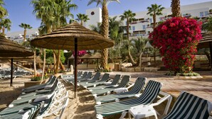 Un resort frente a la playa con sillas de descanso y sombrillas de paja.