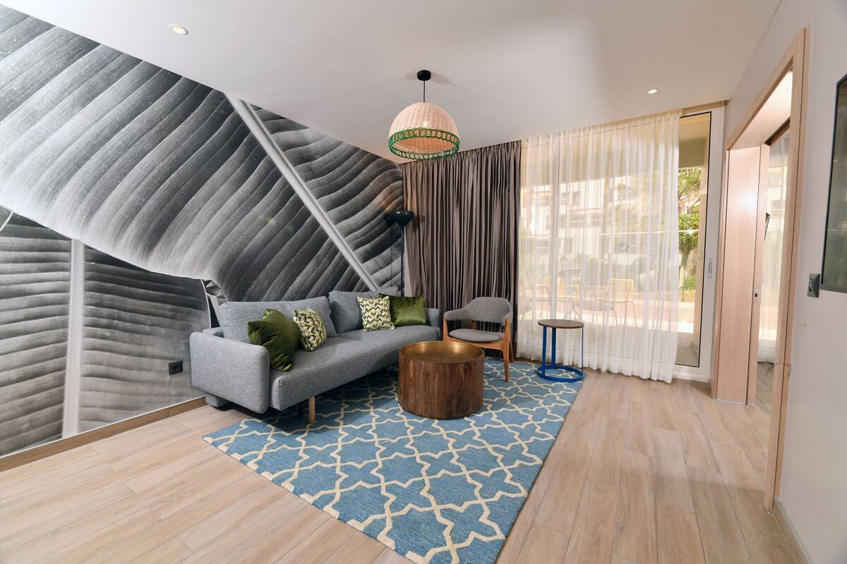 A modern living room with a sofa, a round coffee table, and a patterned rug.