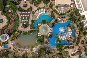 An aerial view of a resort with multiple swimming pools, sun loungers, and palm trees. - Royal Garden by Isrotel Collection (Eilat)