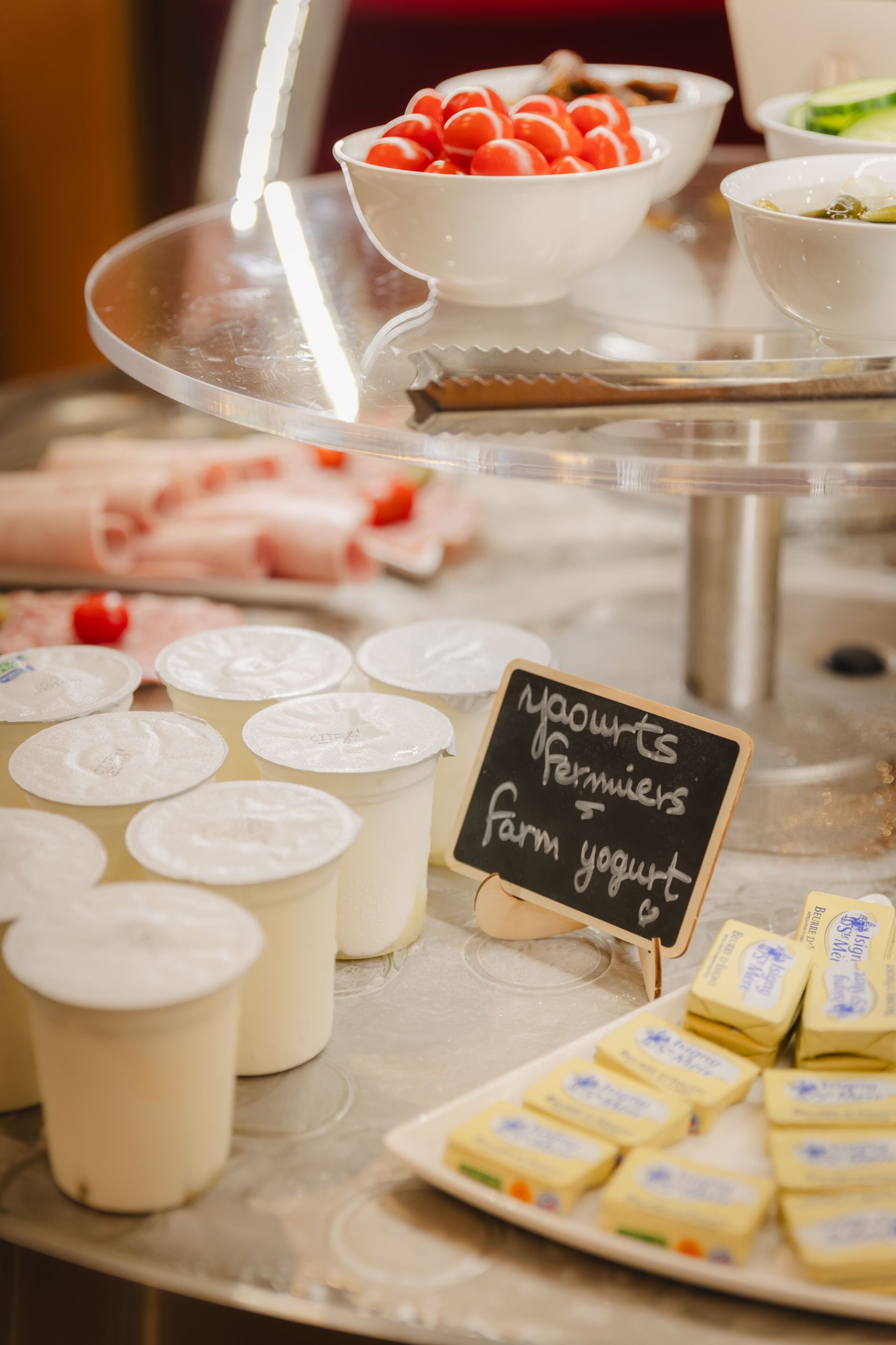 Exposição de laticínios com iogurte de fazenda, queijo e tomates.