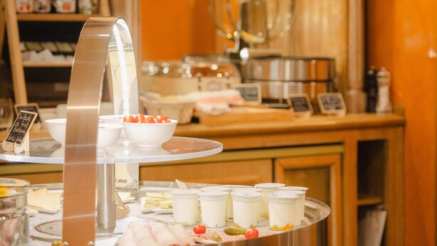 A buffet area with various food items and a display of white ceramic dishes. - Grand Hotel Dore (Paris)
