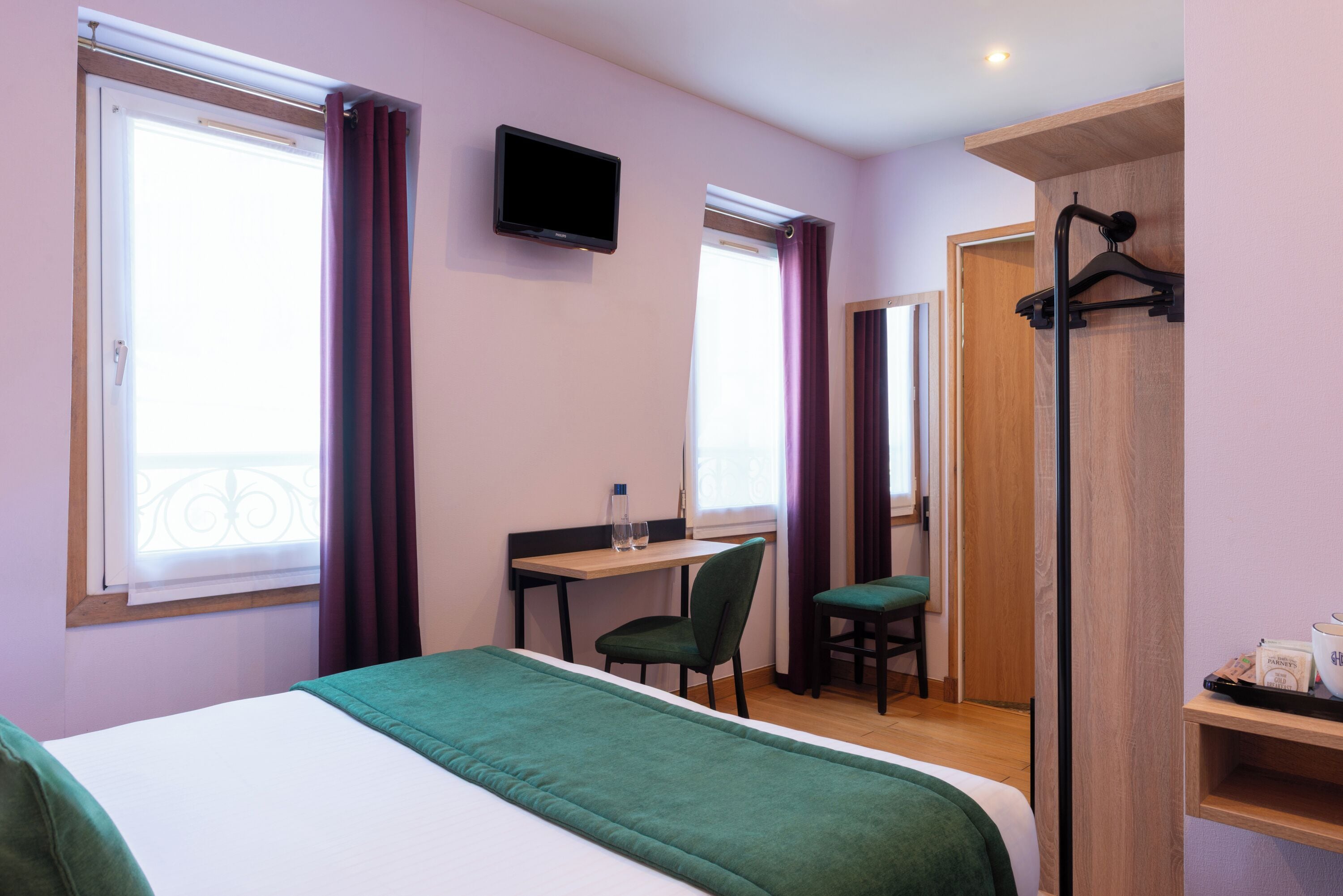 Une chambre d’hôtel comprenant un lit, un bureau, une chaise, une télévision et une armoire.