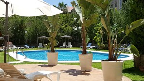 A swimming pool surrounded by potted plants and lounge chairs.