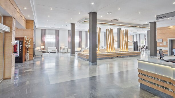 A spacious lobby with a reception desk, seating area, and a decorative water feature.