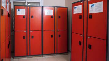 Una fila de taquillas rojas con etiquetas numeradas y una puerta con ventanal.