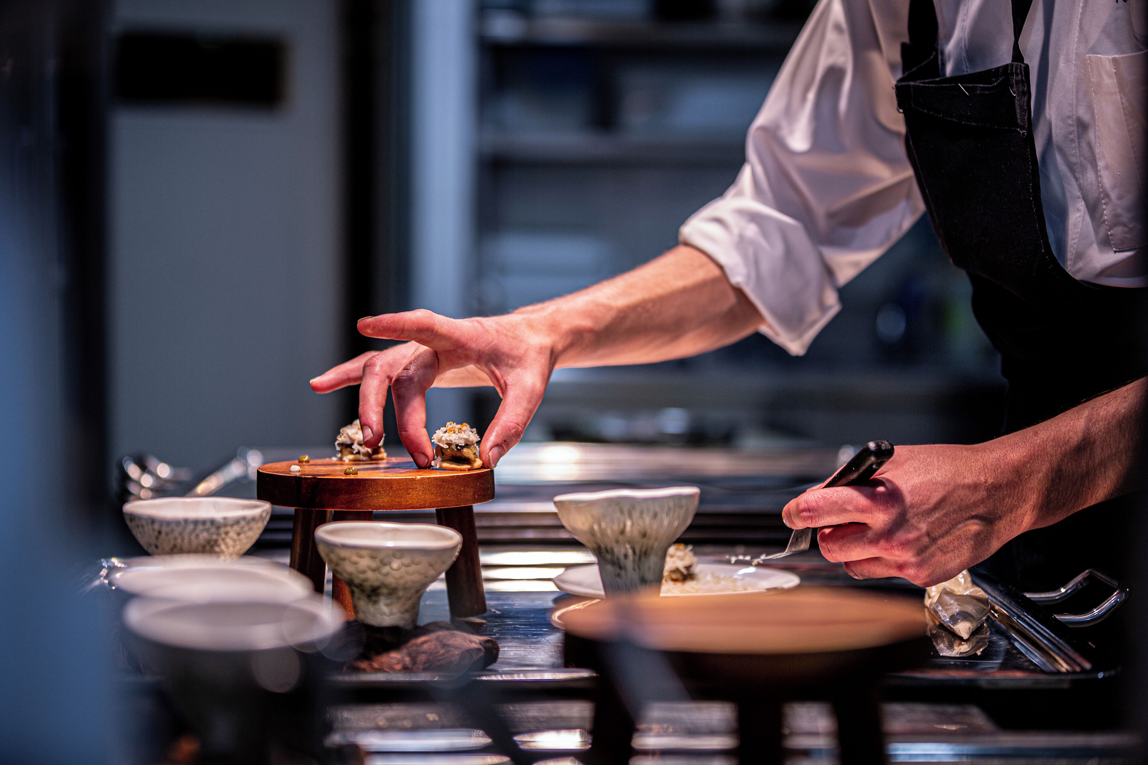 Uma pessoa servindo comida em uma mesa com diversos pratos e utensílios.