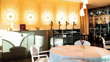 A well-lit restaurant with a round table, chairs, and a wall of illuminated circular designs.