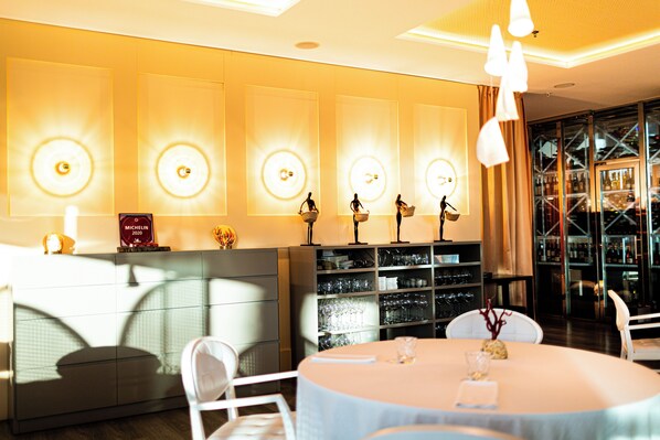Un restaurante bien iluminado con una mesa redonda, sillas y una pared de diseños circulares iluminados.