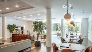 A spacious lobby with a seating area, a dining table, and a large plant. - AR Diamante Beach Spa & Convention Center (Calpe)