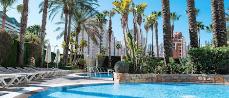 A pool area with lounge chairs and palm trees.