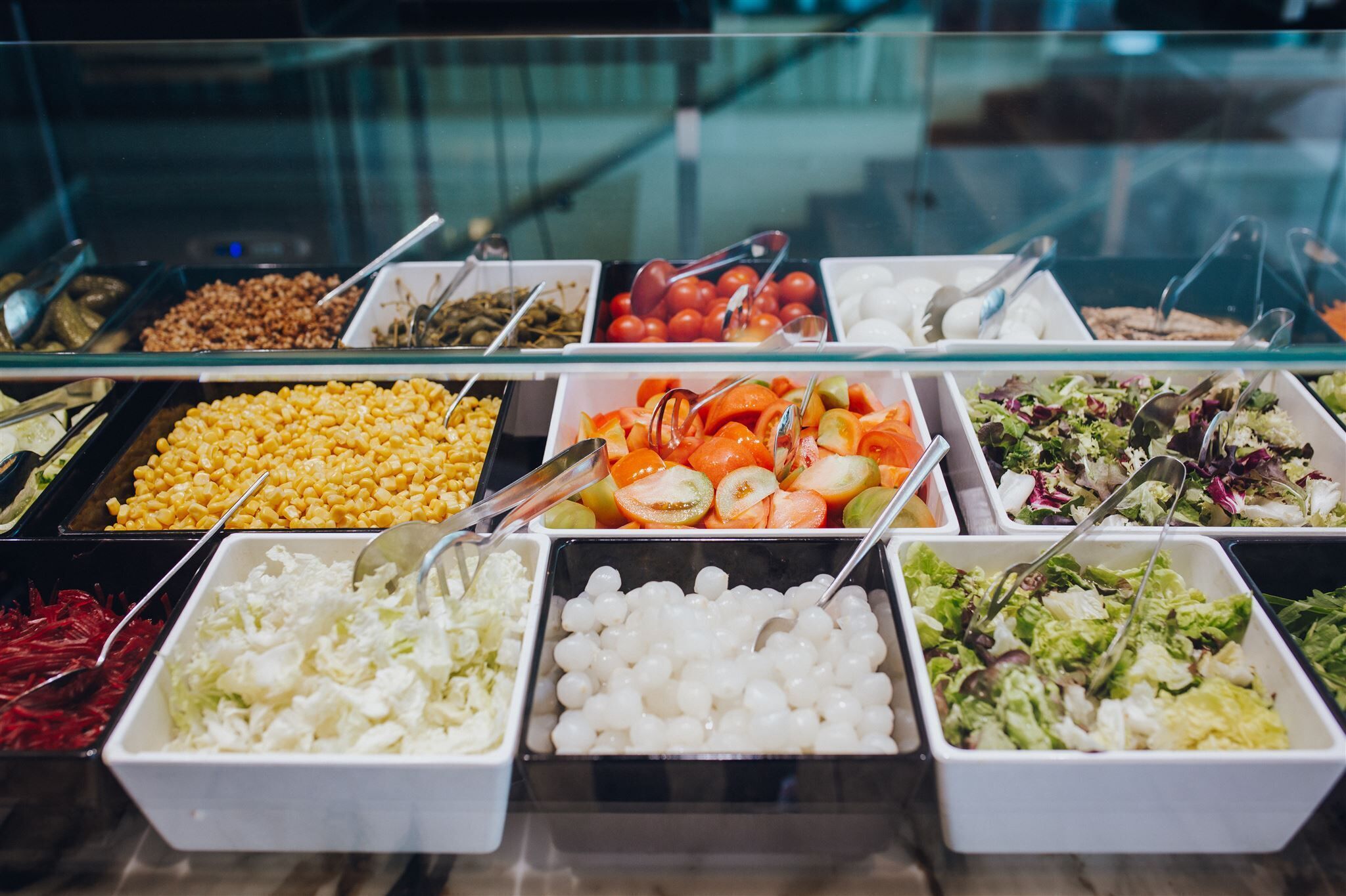En buffet med forskellige spisemuligheder, herunder majs, gulerødder, tomater og salater.