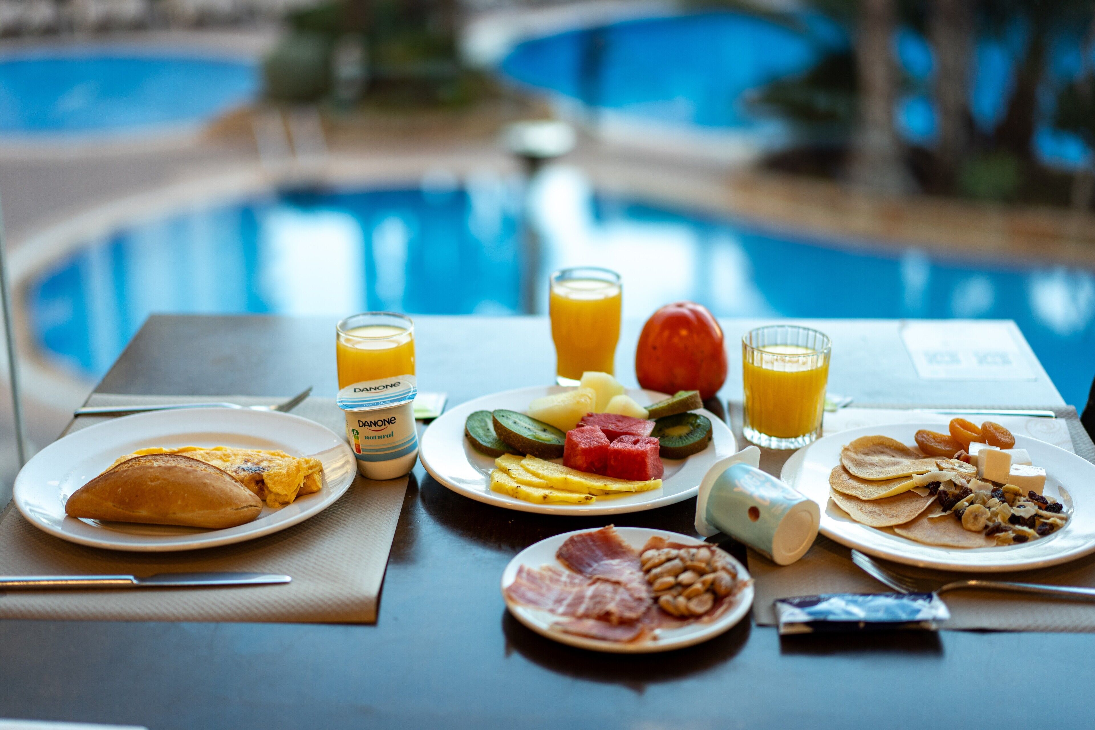 Una mesa de desayuno con platos de comida, jugo y una servilleta.