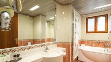 Ein Badezimmer mit einem Doppelwaschbecken, einem großen Spiegel, einer Badewanne und einem Fenster.