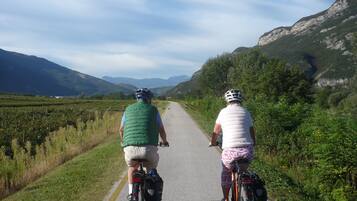 Zwei Radfahrer auf einer asphaltierten Straße vor einer Bergkulisse.