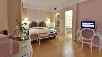 A hotel room with a bed, a desk with a computer, a TV, and a chair.