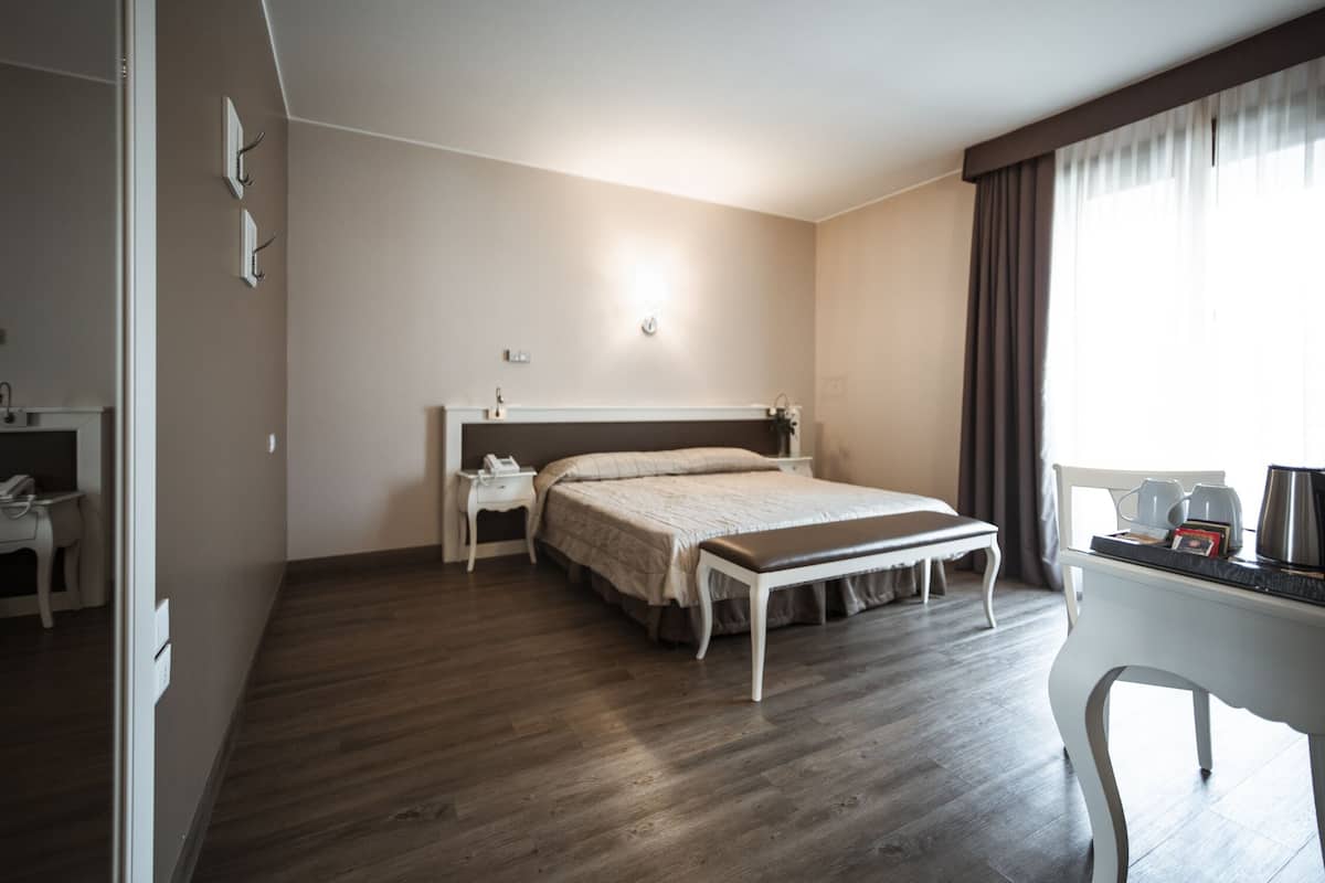 A hotel room with a bed, bedside tables, a desk, and a chair.