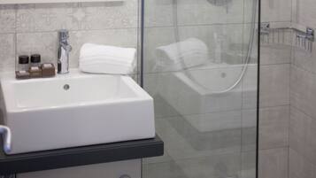 A bathroom with a white sink, a glass shower enclosure, and a tiled wall.