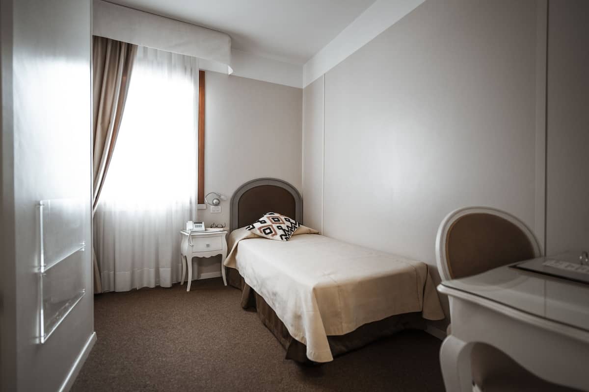 A bedroom with a bed, a desk, a chair, and a dresser.