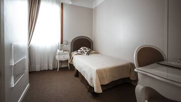 A bedroom with a bed, a desk, a chair, and a dresser.
