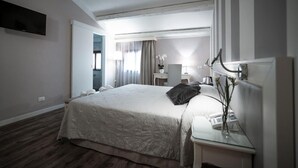 Een hotelkamer met een groot bed, nachtkastje met een lamp, een flatscreen-tv aan de muur en uitzicht naar buiten door een deur.
