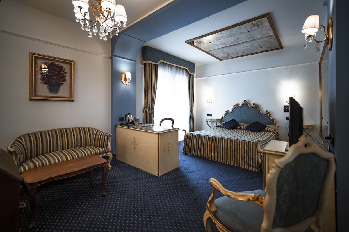 A hotel room with a sofa, a desk, a bed, and a chair.