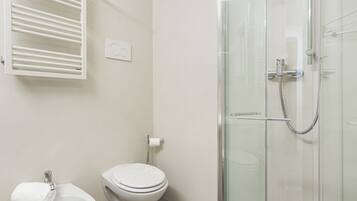 Un baño moderno con ducha de vidrio, inodoro y bidé.