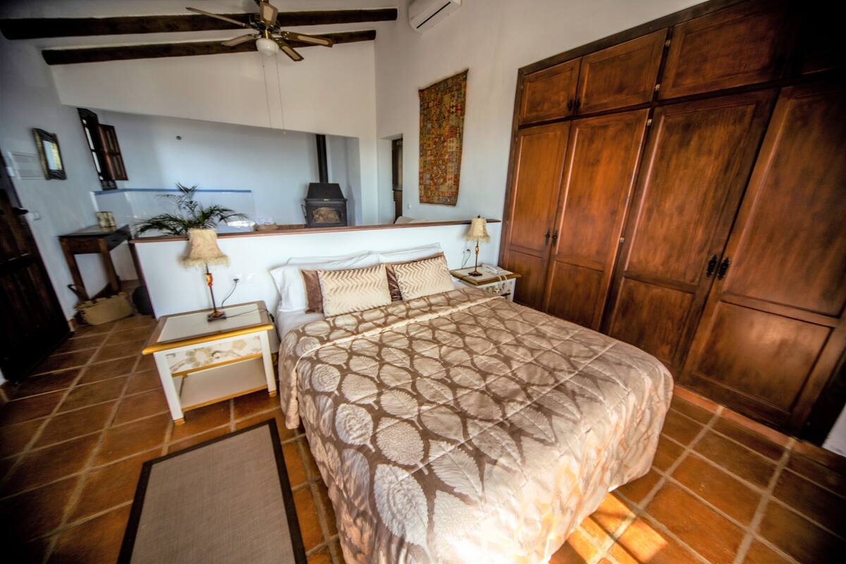 Un dormitorio con una cama grande, un armario de madera y un ventilador de techo.