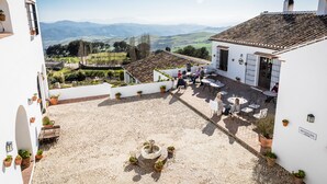 Un patio con una fuente, asientos al aire libre y vistas a montañas distantes.