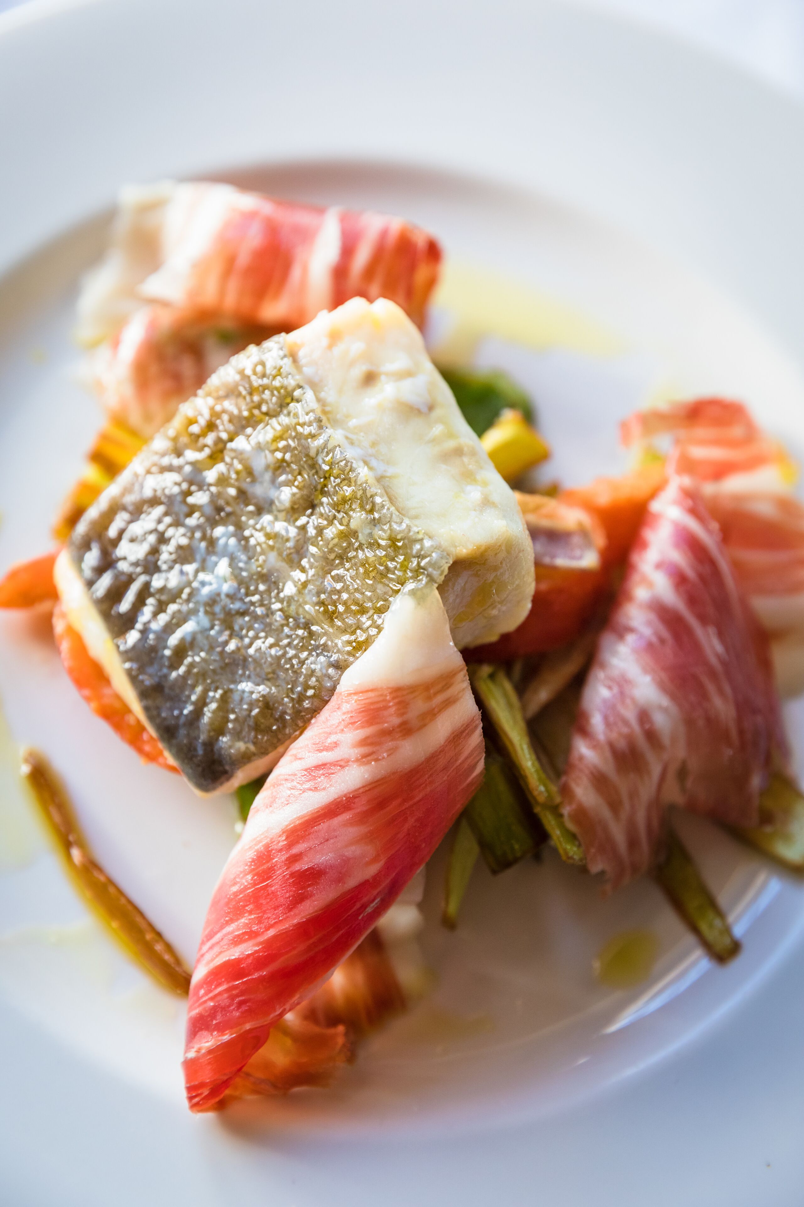 A dish with fish, vegetables, and possibly some meat on a plate.