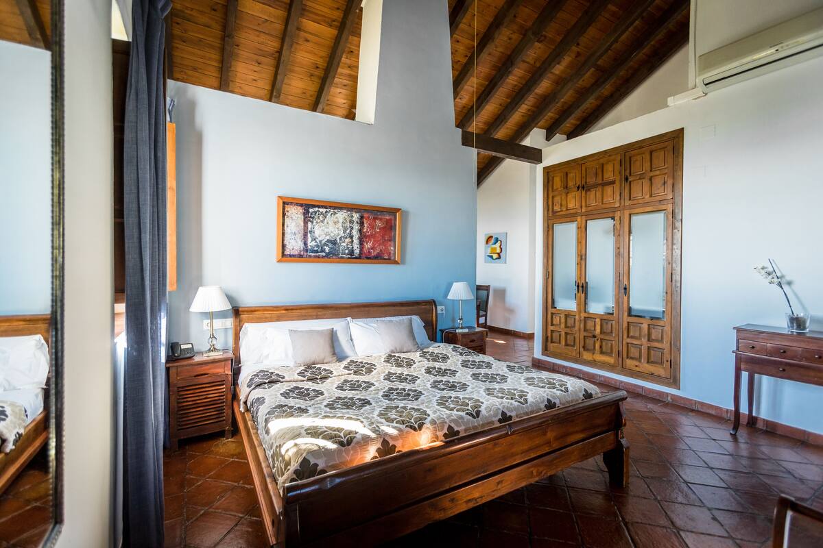 Un dormitorio con cama de madera, una mesita de noche, una lámpara, un armario y un espejo.