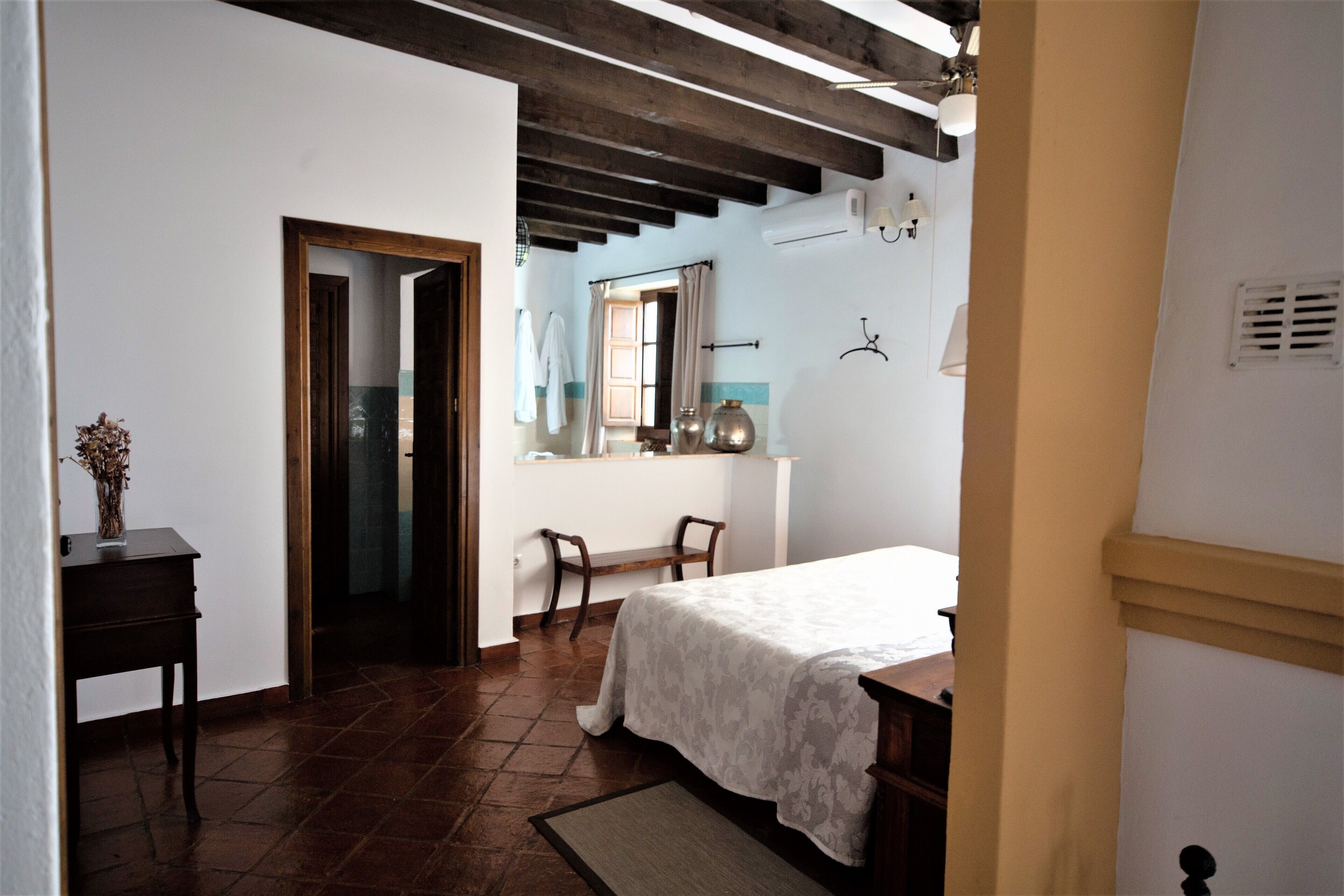 Een slaapkamer met een bed, bureau, stoel en raam met gordijnen.