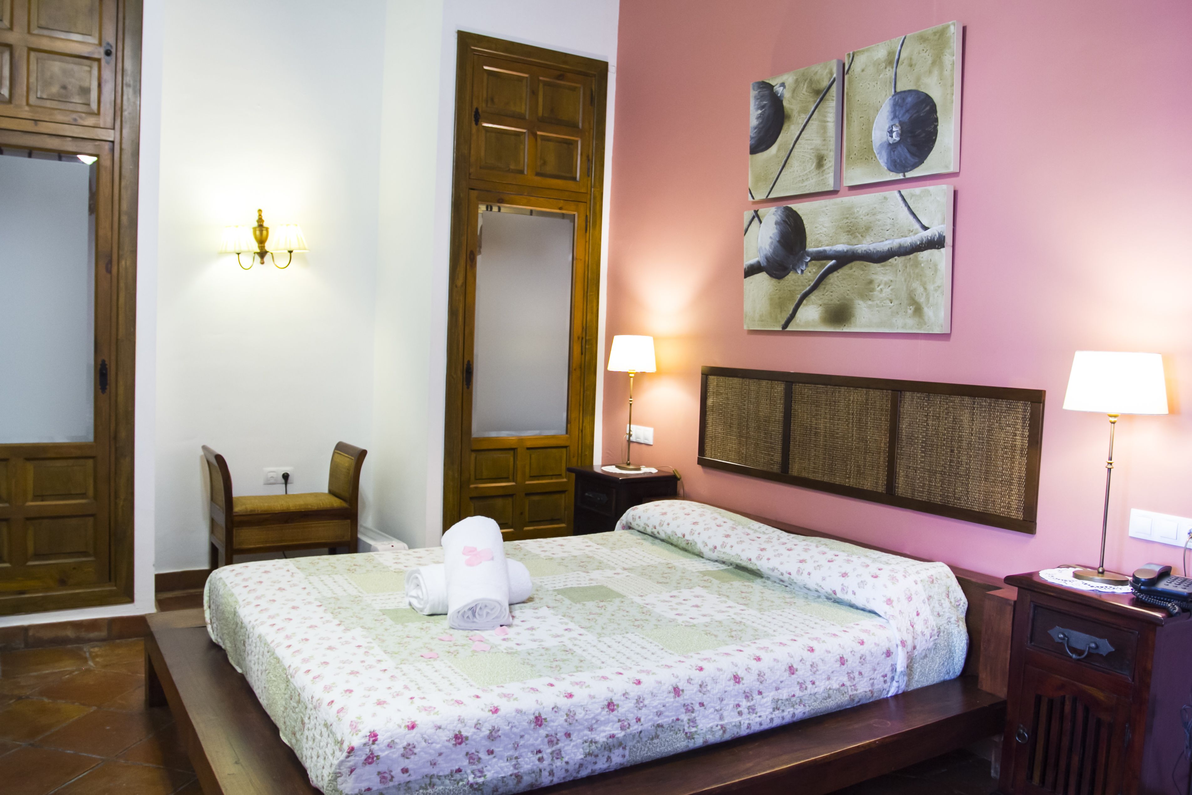 A bedroom with a bed, a chair, a nightstand, and a wall-mounted lamp.