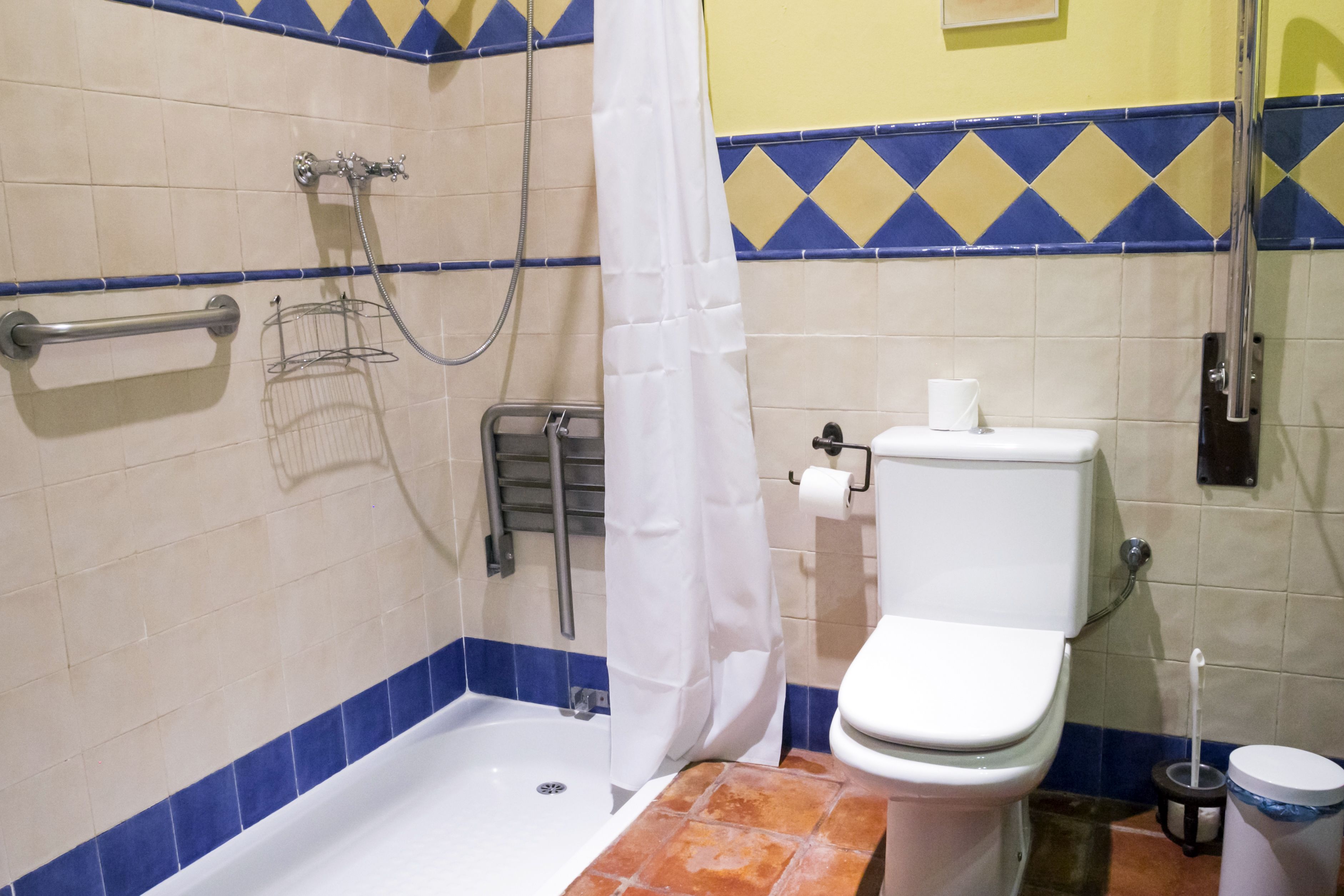 Un baño con bañera, inodoro, ducha y barra de apoyo.