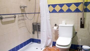 Un baño con bañera, inodoro, ducha y barra de apoyo.