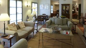 A spacious living room with multiple seating areas, a coffee table, and a dining table.