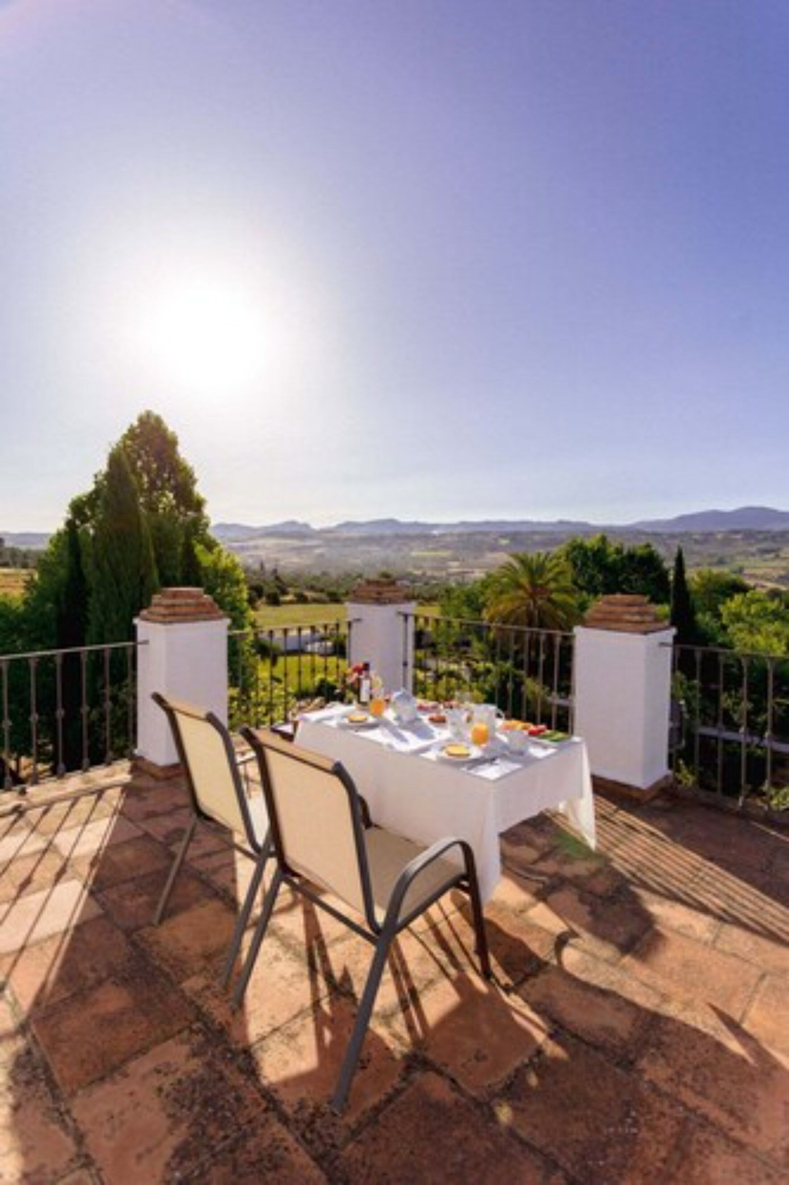 Uma área de refeições ao ar livre com uma mesa posta para dois, com vista para uma paisagem deslumbrante.