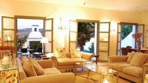 A cozy living room with two sofas, a coffee table, and a view of a white building through open doors. - Hotel Boutique Molino del Arco (Ronda)