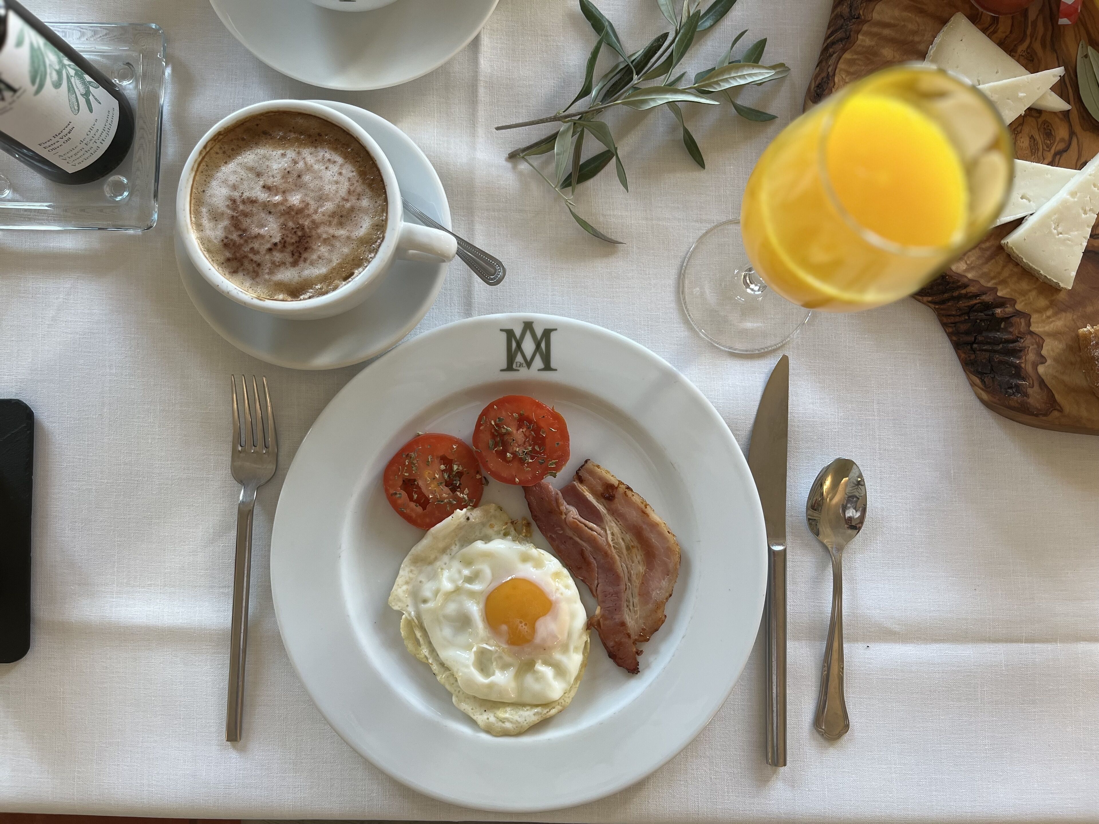 A breakfast setting with a plate of eggs, bacon, and tomatoes, a cup of coffee, and a glass of orange juice.
