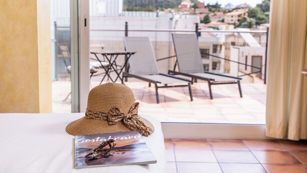 Een strohoed met strik op tafel, bij een brochure met de titel 'Costa Brava'.