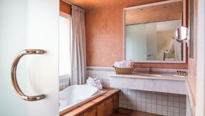 Een badkamer met een bad, een wastafel, een spiegel en een raam met gordijnen.